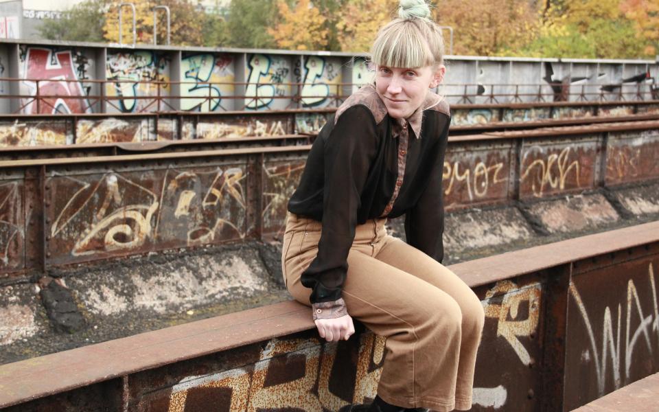 Marie Pooth Porträt von Marie Pooth, sie sitzt auf einer alten Bahnbrücke, im Hintergrund sind Graffitis